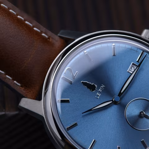 Le Pin dial with the engraved pine-tree emblem and wordmark, on a brown leather strap.