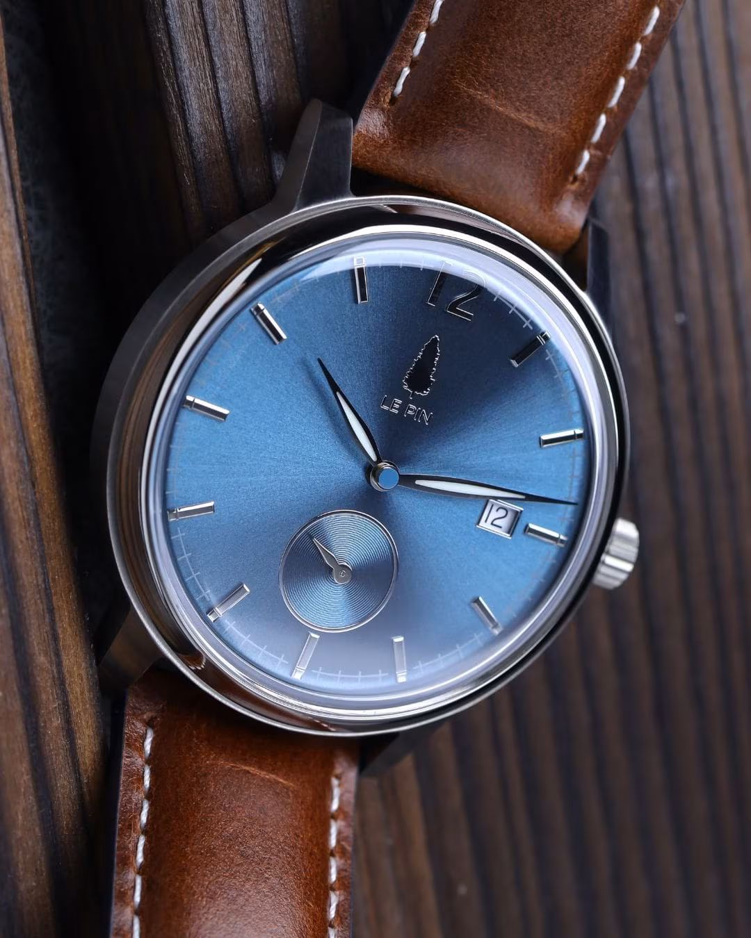 Three-quarter view of the dial with the leather strap curving away.