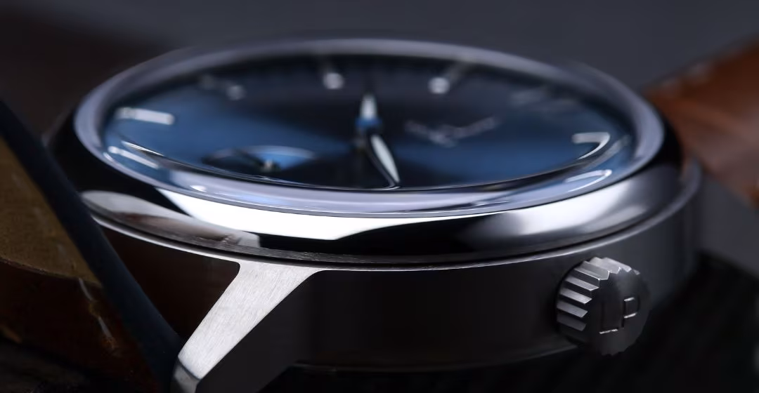 The Le Pin Automatic resting on dark ribbed wood.